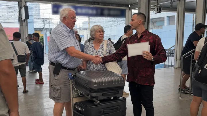Valery shaking hands with a retired couple with suitcases at Mactan airport