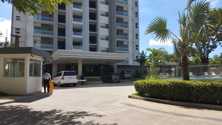 A condo building with a guard house and palm trees in Cebu