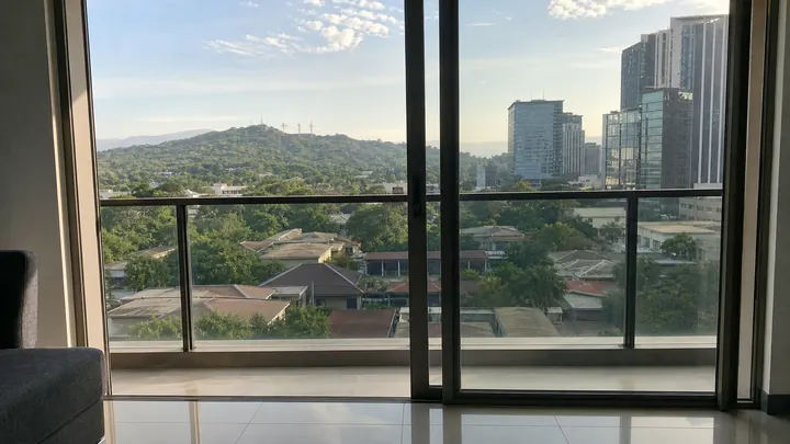 A floor-to-ceiling window with a view of hills and the city