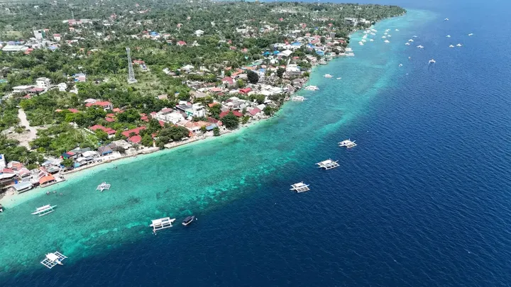 The Moalboal coast from above, turquoise reef water along a green shore